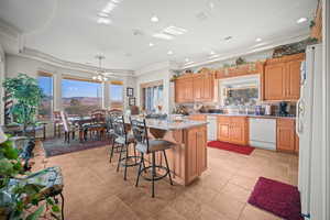 Kitchen with tasteful backsplash, light stone counters, white appliances, a breakfast bar area, and a ceiling fan