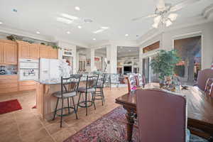 Dining space with crown molding, a ceiling fan, recessed lighting, a fireplace, and light tile patterned floors