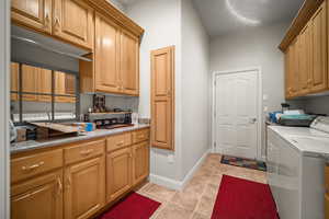 Laundry room featuring washing machine and dryer, light tile patterned floors, and cabinet space
