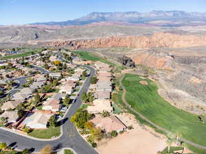 Aerial view of property and surrounding area featuring a mountain backdrop, a local golf course, and nearby suburban area