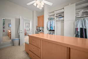 Spacious closet with light colored carpet and a ceiling fan