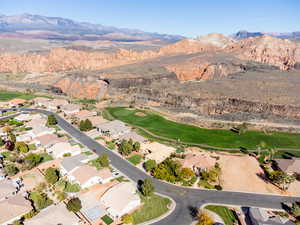 Aerial view of property and surrounding area featuring a mountain backdrop and nearby suburban area