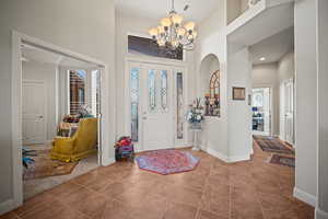 Foyer entrance with a high ceiling, tile patterned floors, and a chandelier