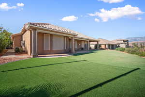 Back of property featuring stucco siding, a lawn, a mountain view, and a tile roof
