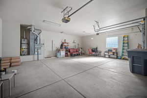 Garage featuring strapped water heater, a garage door opener, and heating unit