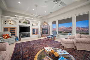 Living area with a raised ceiling, light carpet, built in features, a fireplace, and recessed lighting