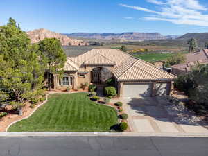 Mediterranean / spanish-style house with a front yard, an attached garage, a mountain view, concrete driveway, and stucco siding