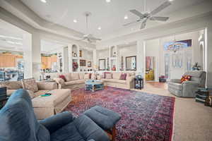 Living area with a raised ceiling, recessed lighting, carpet flooring, and a chandelier
