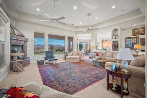 Carpeted living room featuring a tray ceiling, a fireplace, and recessed lighting