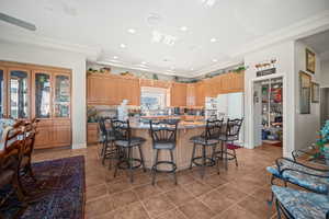 Kitchen featuring a spacious island, a breakfast bar, recessed lighting, white appliances, and dark stone counters