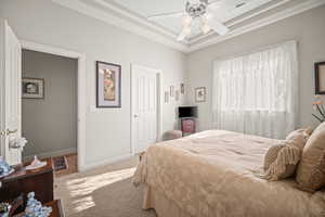 Bedroom with light colored carpet, a ceiling fan, and a raised ceiling