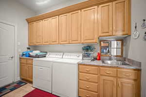 Laundry area with washing machine and clothes dryer and light tile patterned floors