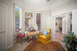 Living area featuring light colored carpet, a chandelier, light tile patterned floors, and a ceiling fan