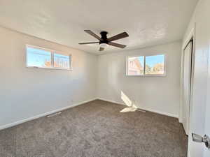 Unfurnished bedroom with dark colored carpet, ceiling fan, a closet, and a textured ceiling