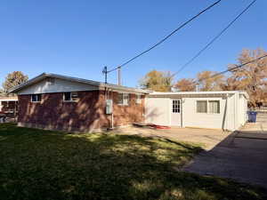 Back of property with brick siding, a yard, and a patio