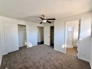 Unfurnished bedroom with two closets, carpet, a textured ceiling, ceiling fan, and connected bathroom