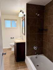 Bathroom with a textured ceiling, shower / bathtub combination, vanity, and tile patterned floors