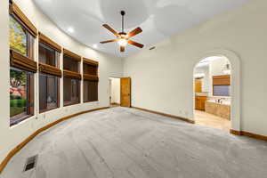 Unfurnished bedroom featuring a ceiling fan, light carpet, recessed lighting, arched walkways, and ensuite bathroom