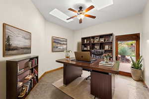 Office area with a ceiling fan and a skylight