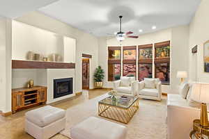 Living room featuring a glass covered fireplace, a ceiling fan, and recessed lighting