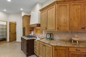 Kitchen with light stone counters, decorative backsplash, oven, light flooring, and recessed lighting