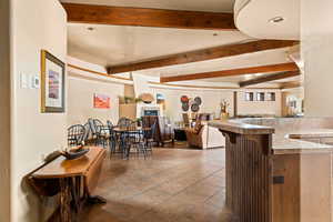 Dining room featuring beam ceiling, light tile patterned floors, bar area, and recessed lighting