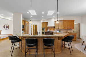 Kitchen with a skylight, a breakfast bar area, light stone countertops, and decorative light fixtures