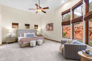 Bedroom featuring carpet floors, a ceiling fan, multiple windows, and a high ceiling