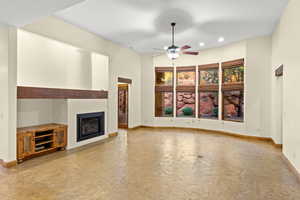 Unfurnished living room featuring a glass covered fireplace, ceiling fan, and recessed lighting