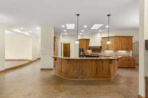Kitchen featuring light stone counters, hanging light fixtures, tasteful backsplash, a kitchen breakfast bar, and a skylight