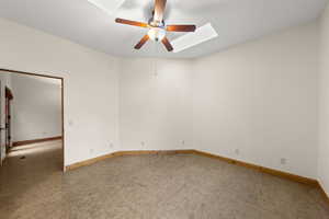 Unfurnished room with light colored carpet, a skylight, and a ceiling fan