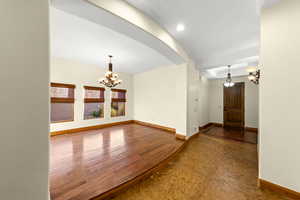 Spare room with a chandelier and dark wood-type flooring