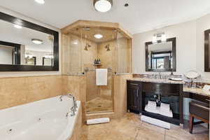 Bathroom featuring a tub with jets, vanity, a shower stall, and light tile patterned flooring