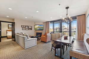 Dining space featuring a lit fireplace, recessed lighting, carpet flooring, and a chandelier