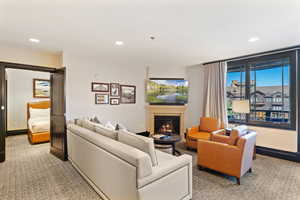 Living room featuring light colored carpet, a glass covered fireplace, and recessed lighting