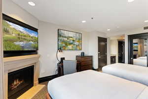 Bedroom featuring recessed lighting, a high end fireplace, speckle patterned floor, and a closet