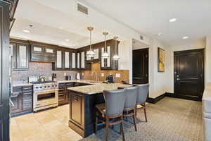 Kitchen with light stone counters, decorative backsplash, decorative light fixtures, a breakfast bar area, and recessed lighting
