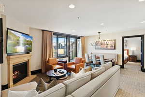 Living room featuring recessed lighting, a lit fireplace, carpet, and a chandelier