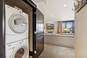 Washroom with recessed lighting, stacked washer / drying machine, and a fireplace