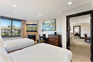 Bedroom with recessed lighting, light carpet, and a glass covered fireplace