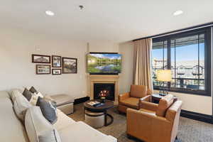 Carpeted living area featuring recessed lighting and a glass covered fireplace
