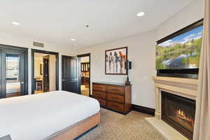 Bedroom featuring recessed lighting, light colored carpet, and a fireplace with flush hearth