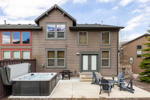 Rear view of property featuring a patio, a hot tub, french doors, and a shingled roof