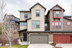 View of front of property with stone siding, concrete driveway, and a garage
