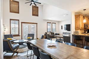 Dining area with french doors, a towering ceiling, dark wood-style floors, and ceiling fan