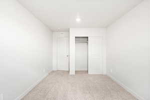 Unfurnished bedroom featuring light colored carpet and a closet