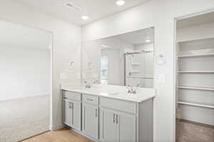 Bathroom featuring double vanity, a shower stall, light colored carpet, light wood-style floors, and recessed lighting