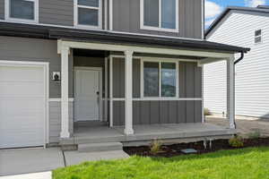 **DISCLAIMER - INTERIOR & EXTERIOR options may vary. (Grass is not included) Doorway to property with board and batten siding, a garage, and a porch