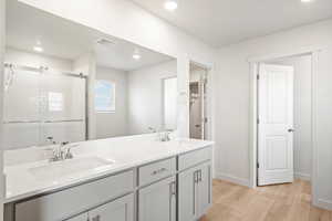 Full bathroom with light wood-style floors, double vanity, a stall shower, and recessed lighting