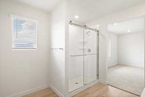 Bathroom with healthy amount of natural light, light wood finished floors, and a shower stall